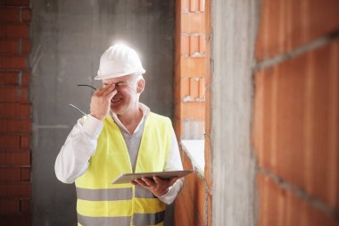 Mühendis inşaat sitedeki bilgisayara ile iş yerinde baş ağrısı ile