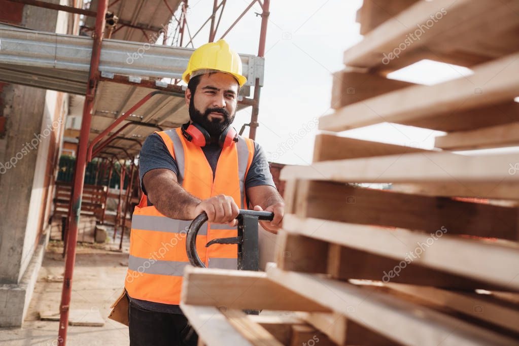 Latino Manual Worker With Forkift Pallet Stacker In Construction Site