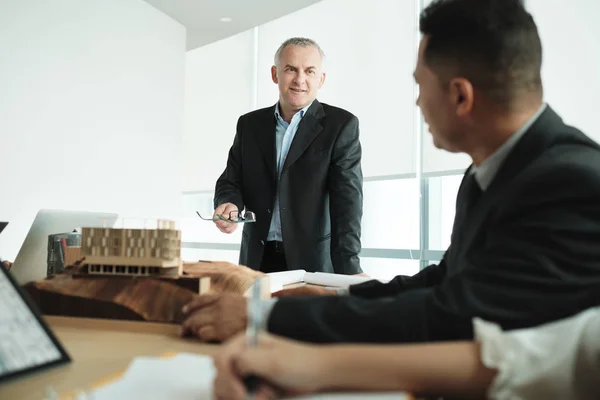 Architect Showing Miniature Building At Business Meeting With Client — Stok fotoğraf