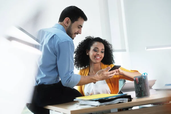 Geschäftsleute lachen im Büro beim Ansehen von Videobildern auf dem Smartphone — Stockfoto