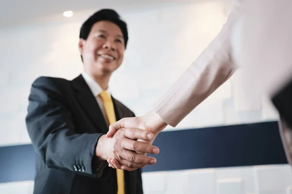 Aperto de mão entre feliz gerente asiático e hispânica empresária no escritório — Fotografia de Stock