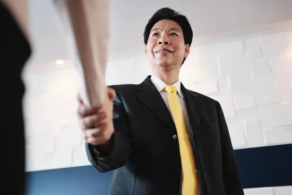 Un apretón de manos entre el feliz gerente asiático y la empresaria hispana en el cargo — Foto de Stock