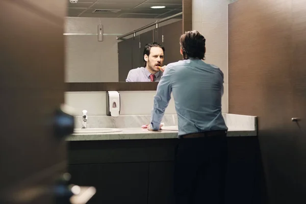 Homem de negócios escovando os dentes após a pausa para o almoço no banheiro do escritório — Fotografia de Stock