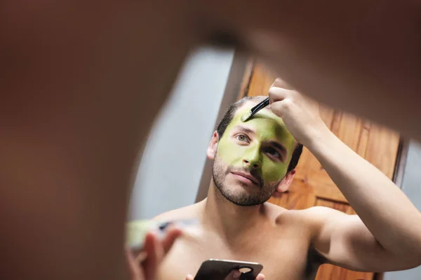 Homme appliquant masque visage pour la beauté masculine dans la salle de bain à la maison — Photo