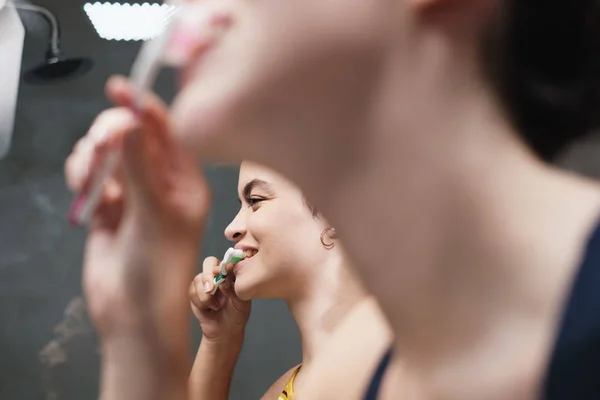 Lesbianas viviendo juntas cepillando dientes en el baño en casa — Foto de Stock