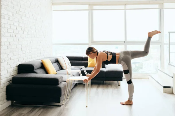 Adulto mulher formação corpo levantando pernas usando cadeira — Fotografia de Stock