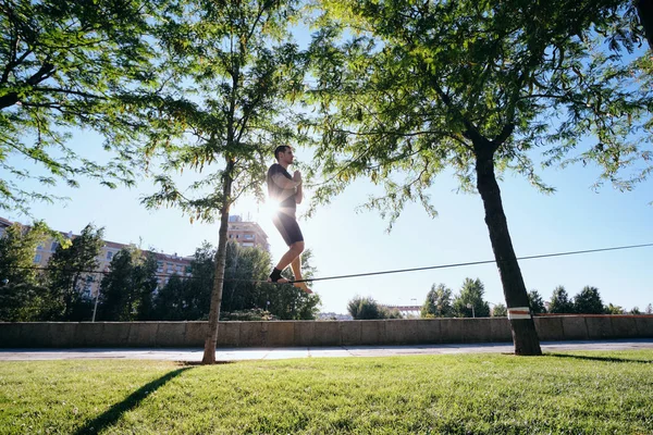 Homem treinando com Slackline Trickline no parque da cidade — Fotografia de Stock