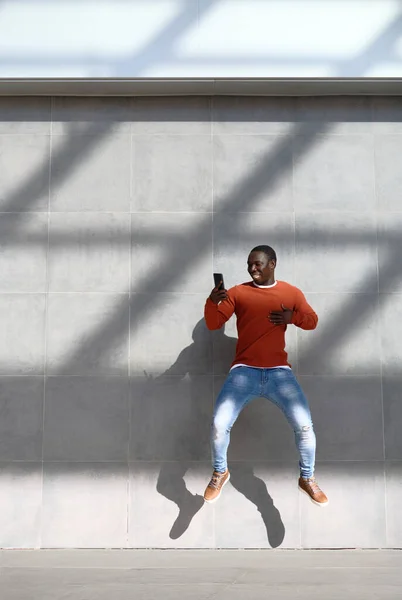 Africano hombre saltar para alegría celebración teléfono — Foto de Stock