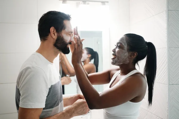 Femme appliquant masque de beauté et nettoyant pour la peau à l'homme — Photo