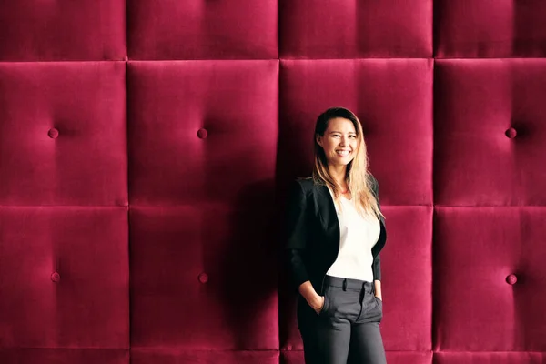 Joven mujer de negocios de pie contra paneles de pared de Borgoña —  Fotos de Stock