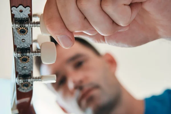 Homem afinando sua guitarra acústica antes de tocar música Imagens De Bancos De Imagens Sem Royalties