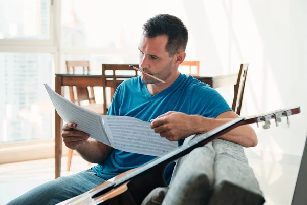 Mid Adult Man Reading Música de Folha de Guitarra Acústica Em Apartamento — Fotografia de Stock