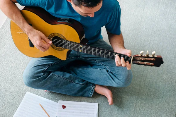 Mid Adult Man Reading Música de Folha de Guitarra Acústica Em Apartamento — Fotografia de Stock