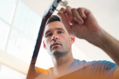 Adam müzik çalmadan önce akustik gitarını akort ediyor.