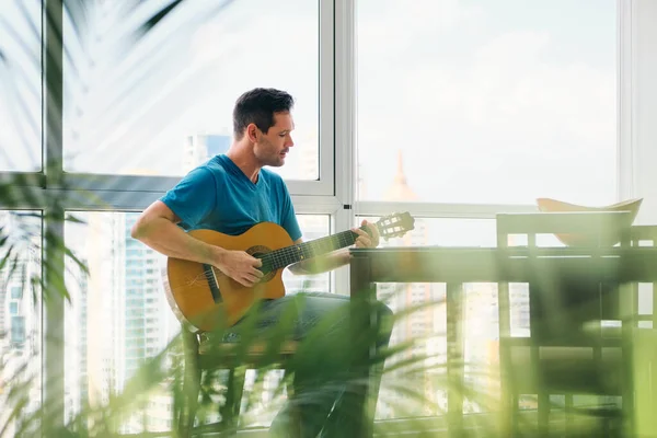 Retrato de homem tocando guitarra clássica e cantando em casa Imagens De Bancos De Imagens