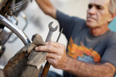 Son sınıf öğrencisi motosikletini inceliyor ve motoru tamir ediyor.