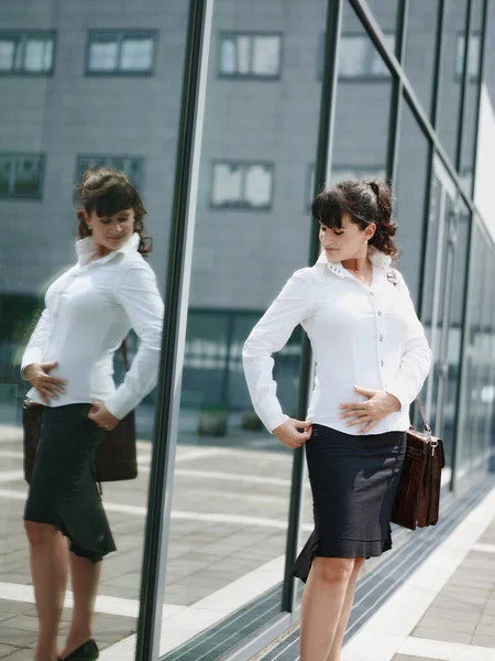 Volwassen vrouw verliezen gewicht en kijken naar spiegel in kantoor venster — Stockfoto
