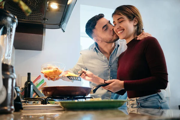 Marido e mulher cozinhando juntos abraçando e beijando — Fotografia de Stock