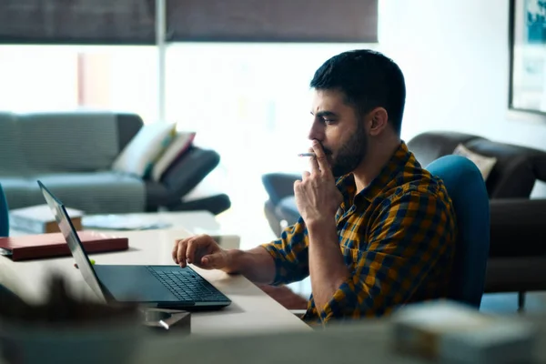 Hombre trabajando desde casa con la computadora y fumar cigarrillos —  Fotos de Stock