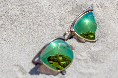 Bir çift güneş gözlüğü güzel bir İspanyol kadın onun tatil keyfini bir yansıması ile sahilde yatıyordu.