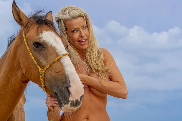 Üstsüz sarışın manken Karayip bir sahilde bir ata biniyor