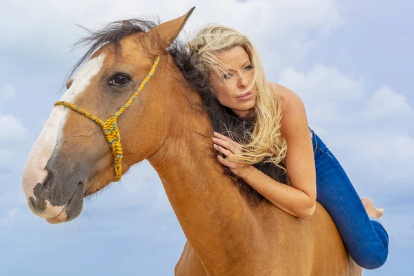 Üstsüz sarışın manken Karayip bir sahilde bir ata biniyor