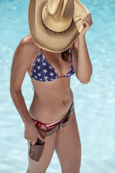 A beautiful American flag bikini model posing with a revolver and holster