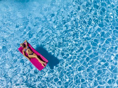 Güzel olgun sarışın bikini modeli, açık havada bir yüzme havuzu pozlar.