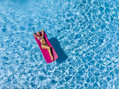 Güzel olgun sarışın bikini modeli, açık havada bir yüzme havuzu pozlar.