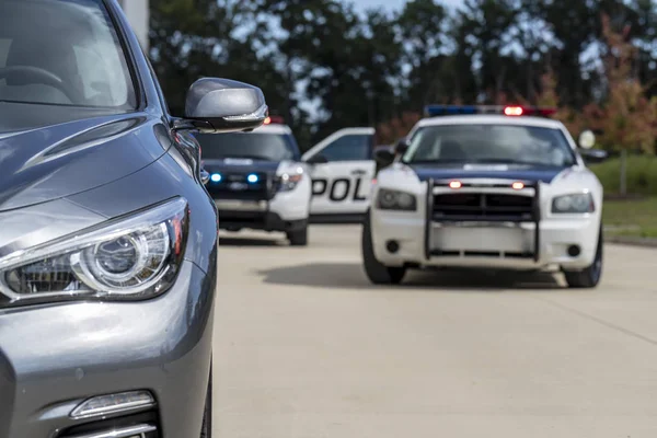 Two police vehicles stop a sedan on a routine traffic stop