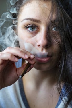 Güzel bir esmer model kendi evinde marihuana içiyor.