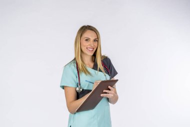 Muhteşem bir sarışın hemşire bir stüdyo ortamında beyaz bir arka plan karşı görevlerini yerine.