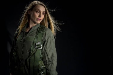 Bir kadın savaş pilotu bir stüdyo ortamında siyah bir arka plan teşkil etmektedir 