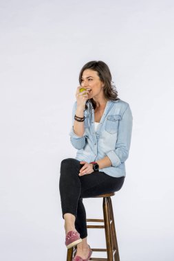 Çok güzel uzun saçlı esmer modeli bir stüdyo ortamında beyaz arka plan karşı bir elma yemek