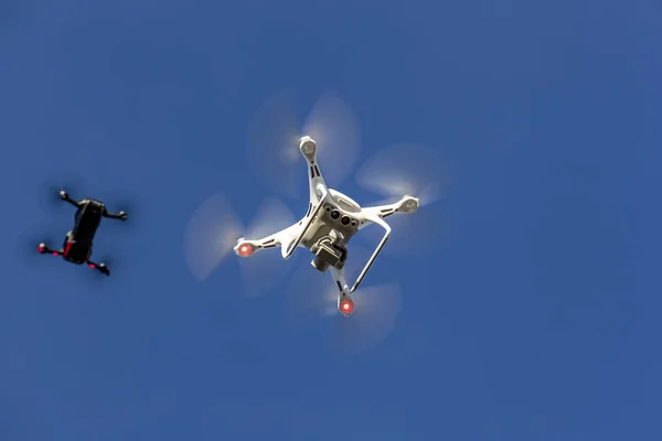 A group of drones fly through the air against a blue sky