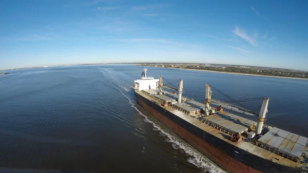 A cargo ship steams towards the open ocean out of a harbor