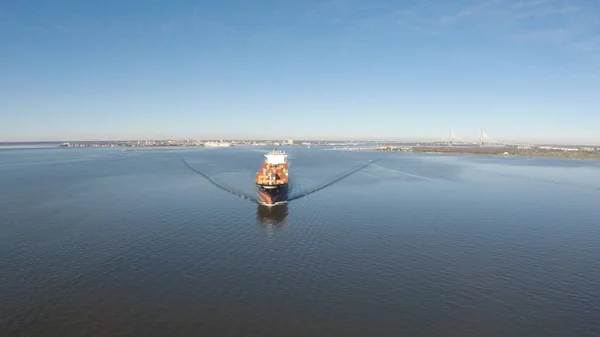 A cargo ship steams towards the open ocean out of a harbor