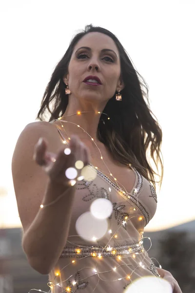 一个华丽的西班牙裔布鲁内特模特在日落时带着小灯站在室外 — 图库照片