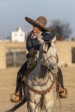 Genç bir Meksikalı Charro kaçarken bir alanda Meksikalı bir çiftlikte güneş doğarken at sürüsü kadar yuvarlar