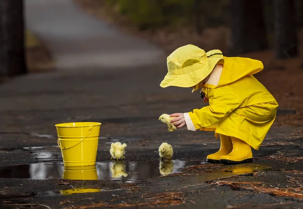 Дитина, насолоджуючись дощ в його Калоші — стокове фото