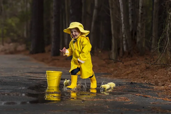 Criança desfrutando da chuva em seus galochas — Fotografia de Stock