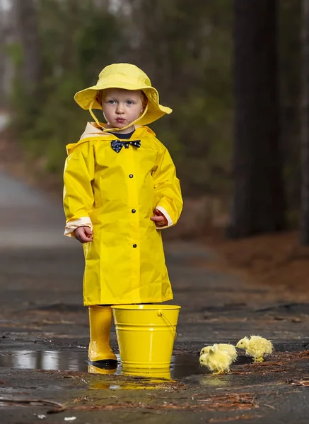 Criança desfrutando da chuva em seus galochas — Fotografia de Stock