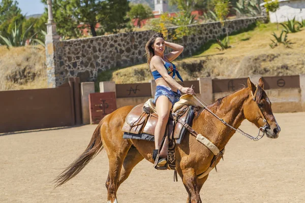 Una encantadora modelo morena hispana posa en un caballo al aire libre en un —  Fotos de Stock