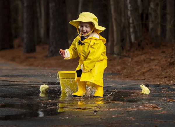 Criança desfrutando da chuva em seus galochas — Fotografia de Stock