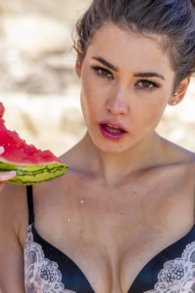 Preciosa morena modelo de bikini relajante en la costa en la playa comiendo almuerzo —  Fotos de Stock