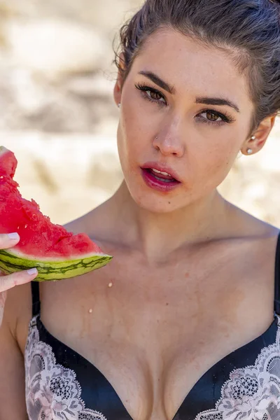 Preciosa morena modelo de bikini relajante en la costa en la playa comiendo almuerzo —  Fotos de Stock