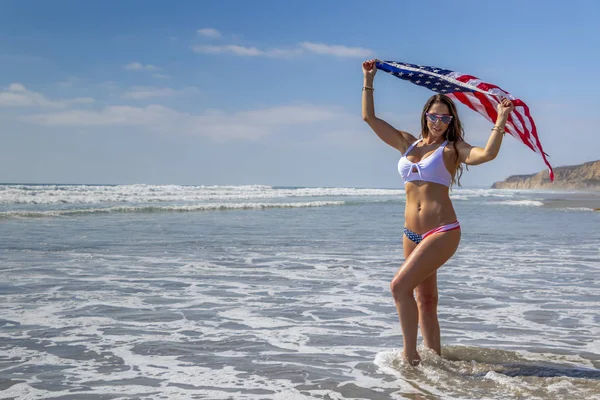 A Lovely Patriotic Brunette Model Poses on the Coast with an Ame — стоковое фото