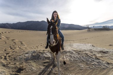 Güzel bir esmer manken, bir yaz günü atını çölde gezdirir. 