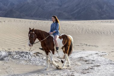 Güzel bir esmer manken, bir yaz günü atını çölde gezdirir. 