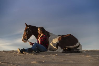 Güzel bir esmer manken, bir yaz günü atını çölde gezdirir. 